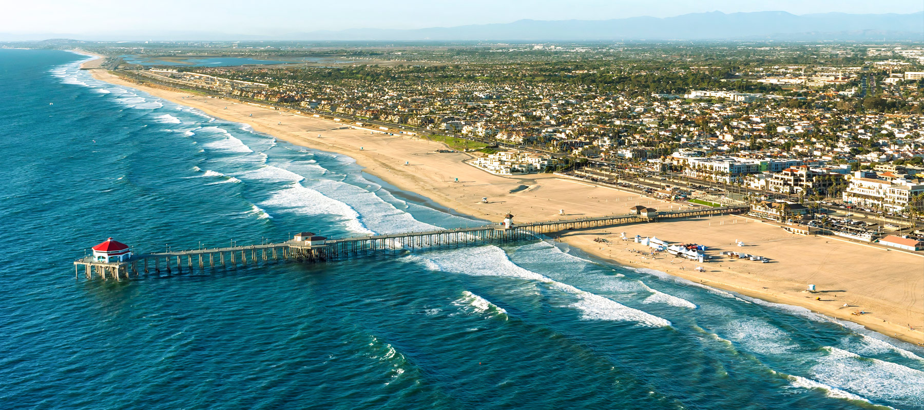 Aerial view of Huntington Beach Pier extending over the ocean with the coastal city beyond