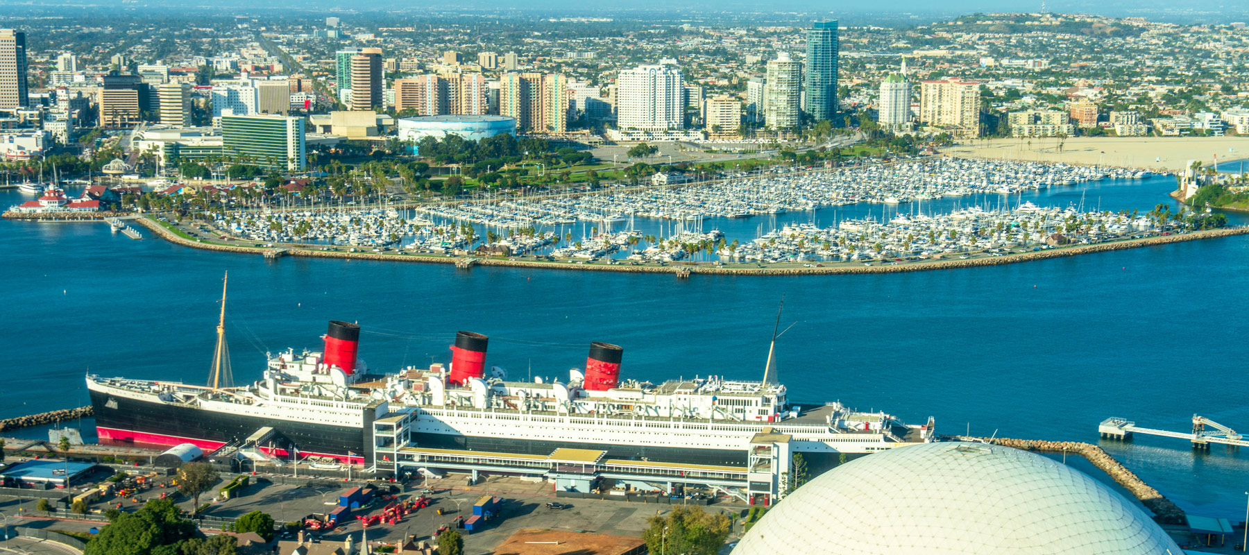 The Queen Mary in Long Beach harbor with the city skyline behind it
