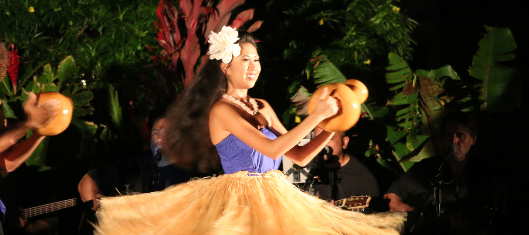 Hula dancer performing with traditional ipu gourd at a Maui luau